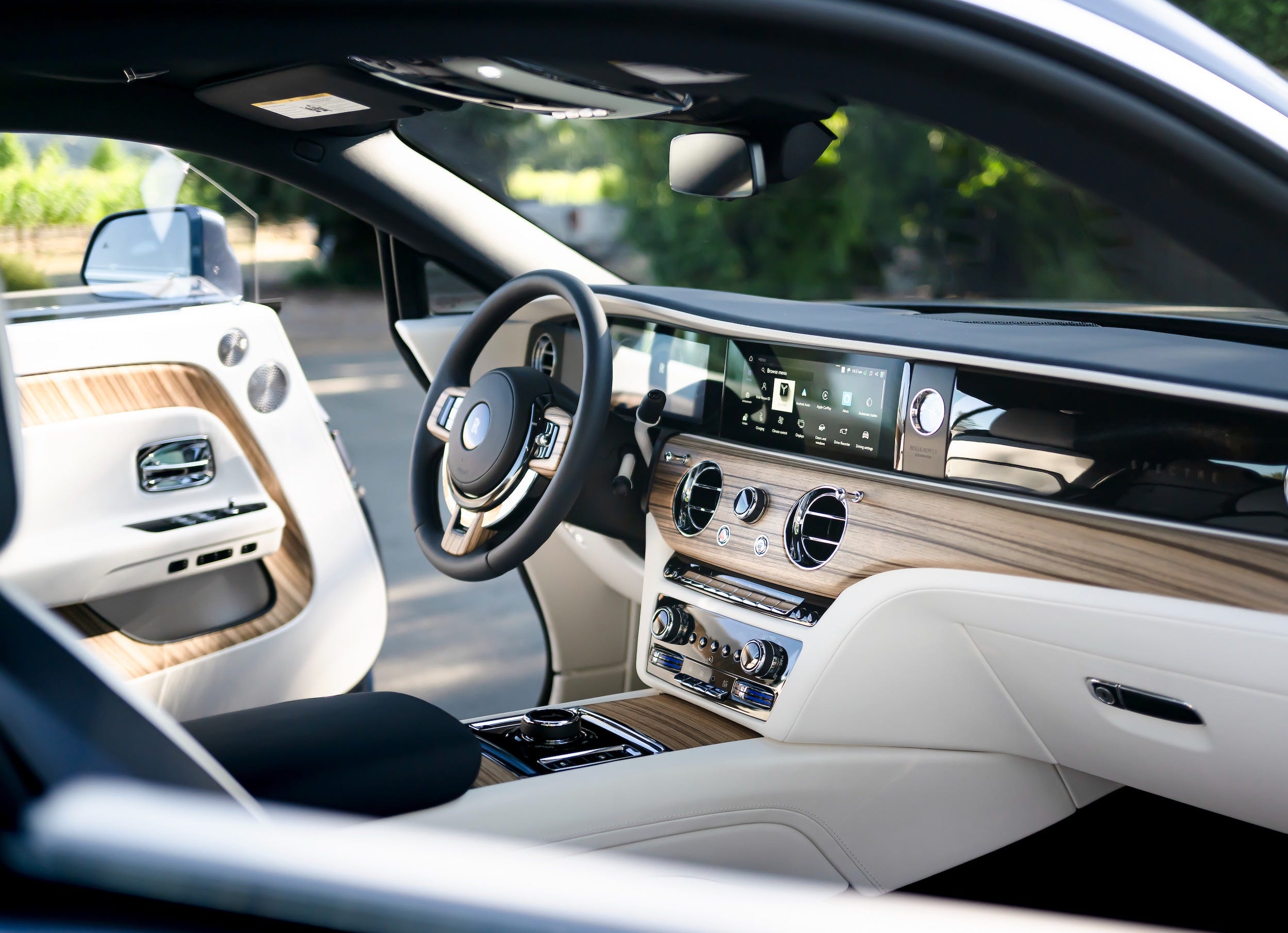 The wood and white-leather interior of a Rolls-Royce Spectre electric car.
